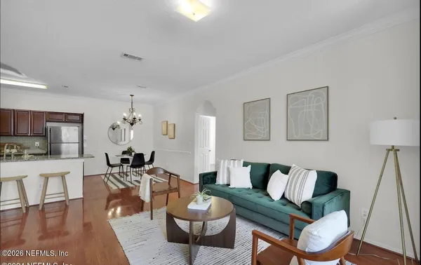 a living room with furniture kitchen view and a wooden floor