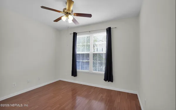 a view of an empty room with window and a ceiling fan