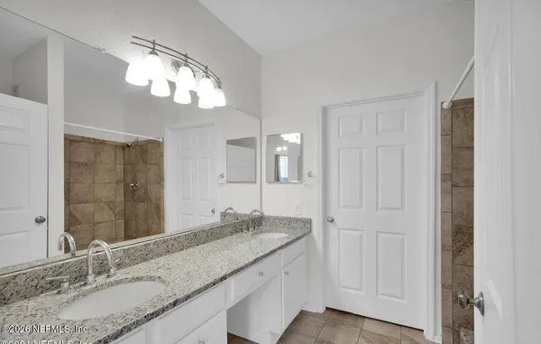 a bathroom with a granite countertop double vanity sink and a mirror
