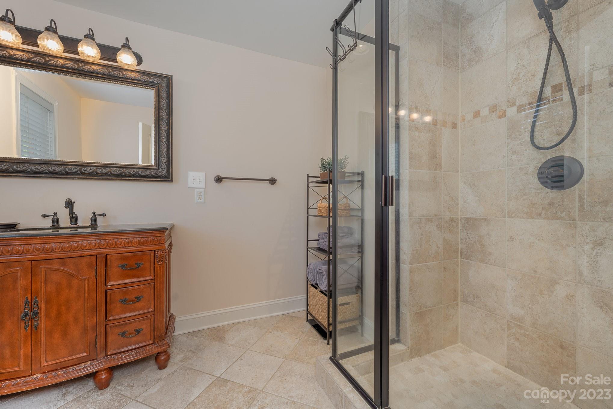 5816 Sharon Road Charlotte, NC 28210 - Photo 19 of 33 a bathroom with a granite countertop sink a mirror a vanity and shower