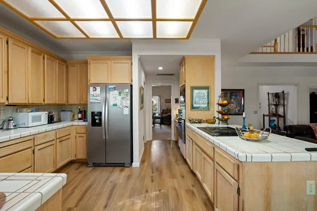 a kitchen with stainless steel appliances granite countertop a stove a sink dishwasher and white cabinets with wooden floor next to windows