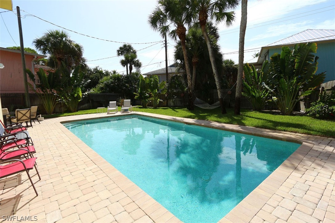 a view of swimming pool with a yard and palm trees