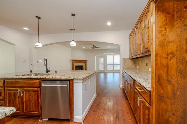 a kitchen with stainless steel appliances granite countertop a sink and wooden floor