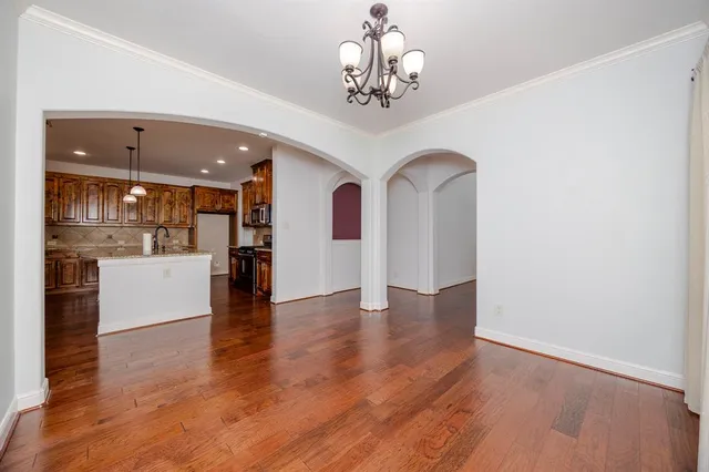 a view of a hallway with wooden floor and a kitchen