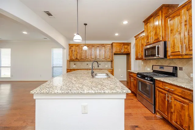 a kitchen with stainless steel appliances granite countertop a sink a stove top oven a counter space and cabinets