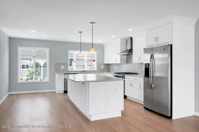 a large kitchen with stainless steel appliances kitchen island granite countertop a refrigerator a oven a island and a wooden floors