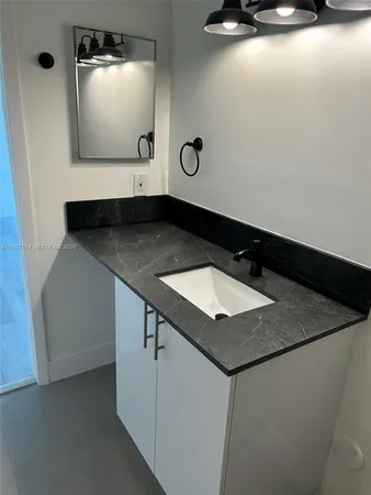 a bathroom with a granite countertop sink and a mirror