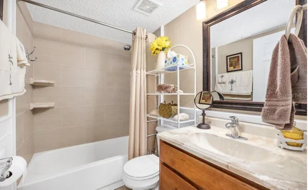 a bathroom with a granite countertop sink a toilet a mirror a vanity a shower and bathtub