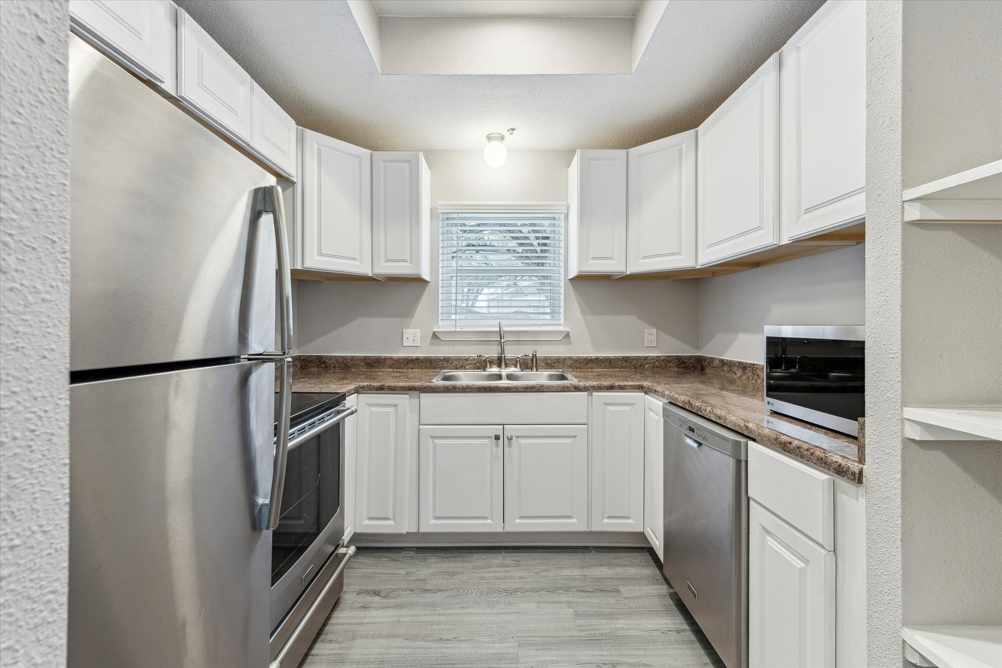 a kitchen with stainless steel appliances granite countertop a refrigerator sink and white cabinets