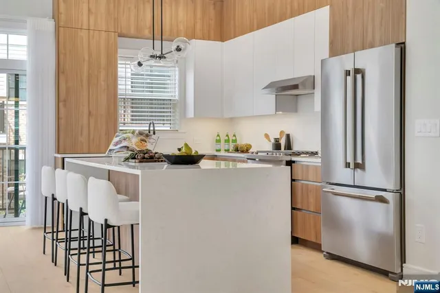 a kitchen with stainless steel appliances granite countertop a refrigerator a sink a stove and a refrigerator