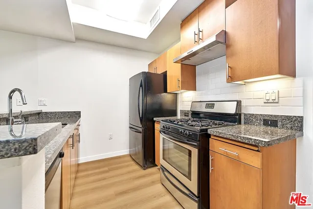 a kitchen with stainless steel appliances granite countertop a sink stove and refrigerator