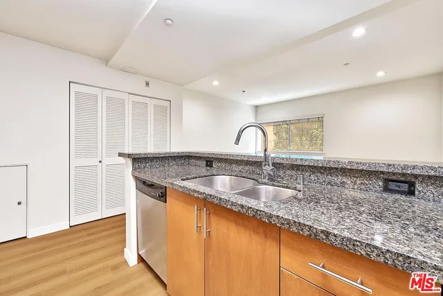 a kitchen with granite countertop a sink and a wooden floor