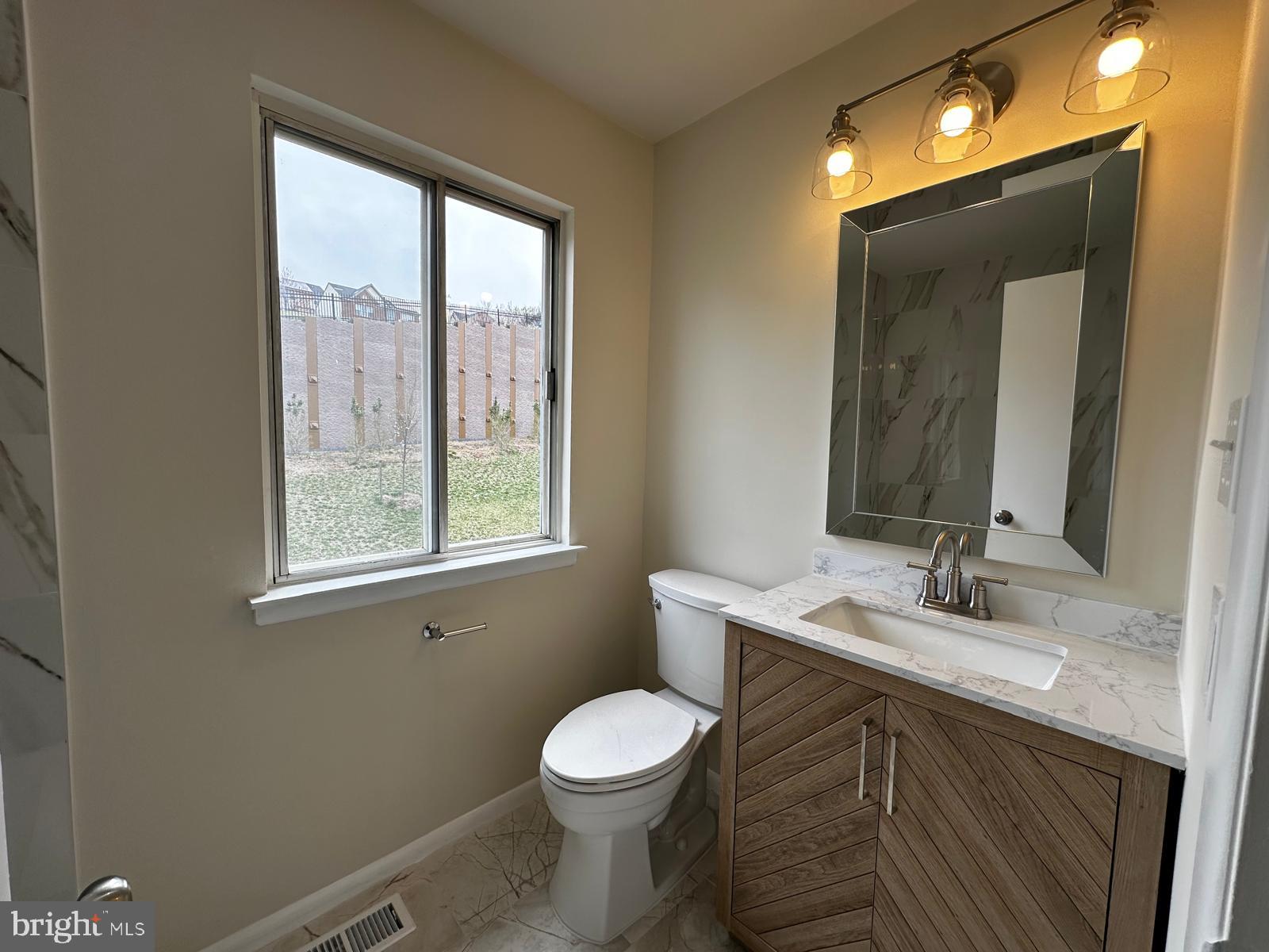 12800 Asbury Drive Fort Washington, MD 20744 - Photo 31 of 53 a bathroom with a toilet a sink a mirror and a window