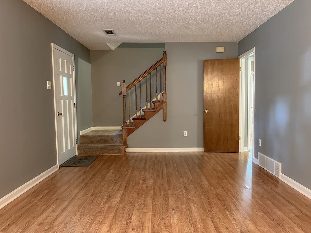 7935 Memphis Arlington Road Bartlett, TN 38133 - Photo 10 of 20 Open living area featuring wood-finish flooring, a multi-paneled entry door, and a staircase with wood banister