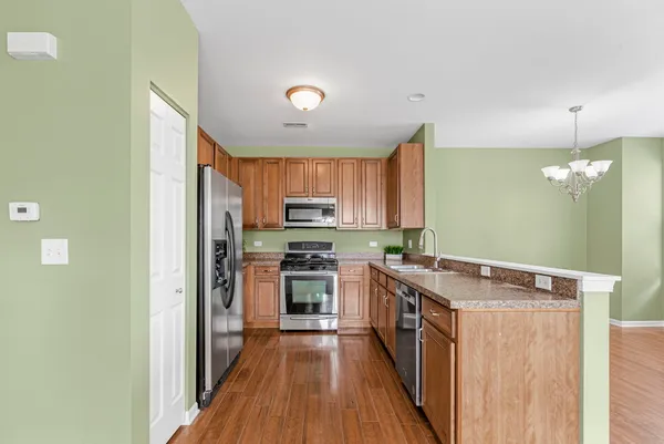 a kitchen with stainless steel appliances granite countertop a stove a sink dishwasher a refrigerator and a oven with wooden floor