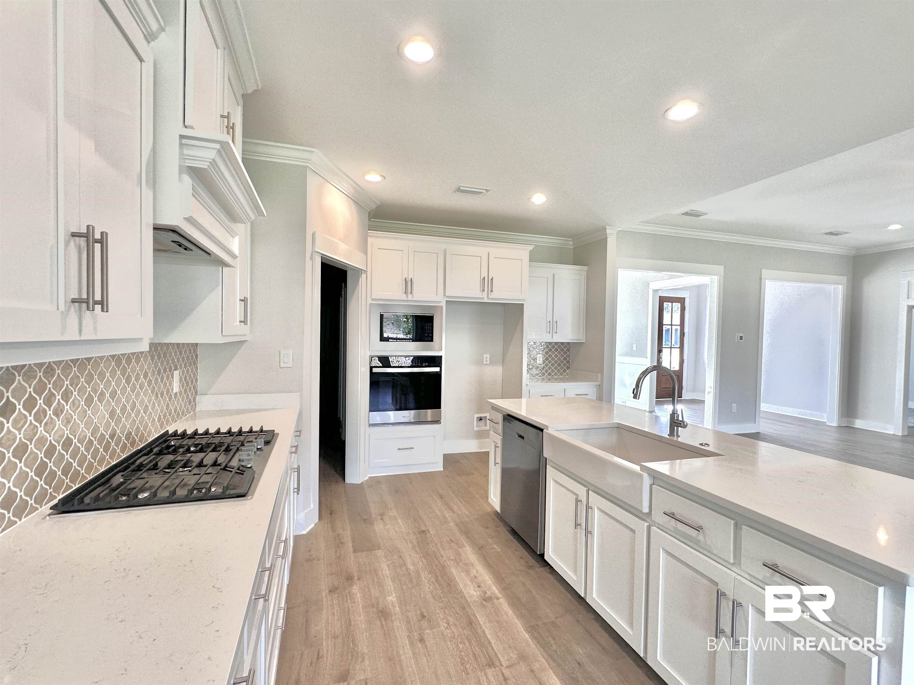 634 Kitfox Avenue Fairhope, AL 36532 - Photo 5 of 33 Kitchen with stainless steel appliances, backsplash, sink, white cabinetry, and light stone counters