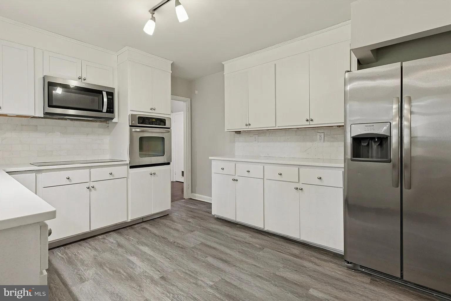 a kitchen with white cabinets stainless steel appliances and wooden floors