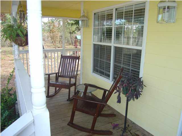 60 Don Graff Road Freeport, FL 32439 - Photo 3 of 15 a porch with a bench and a potted plant next to a window