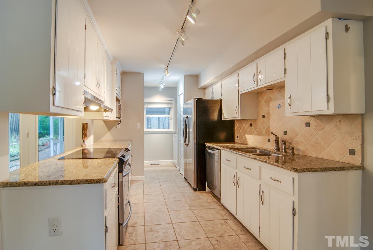 4620 Jimmy Rogers Road Durham, NC 27704 - Photo 10 of 25 a kitchen with stainless steel appliances granite countertop a sink and dishwasher a refrigerator with wooden cabinets