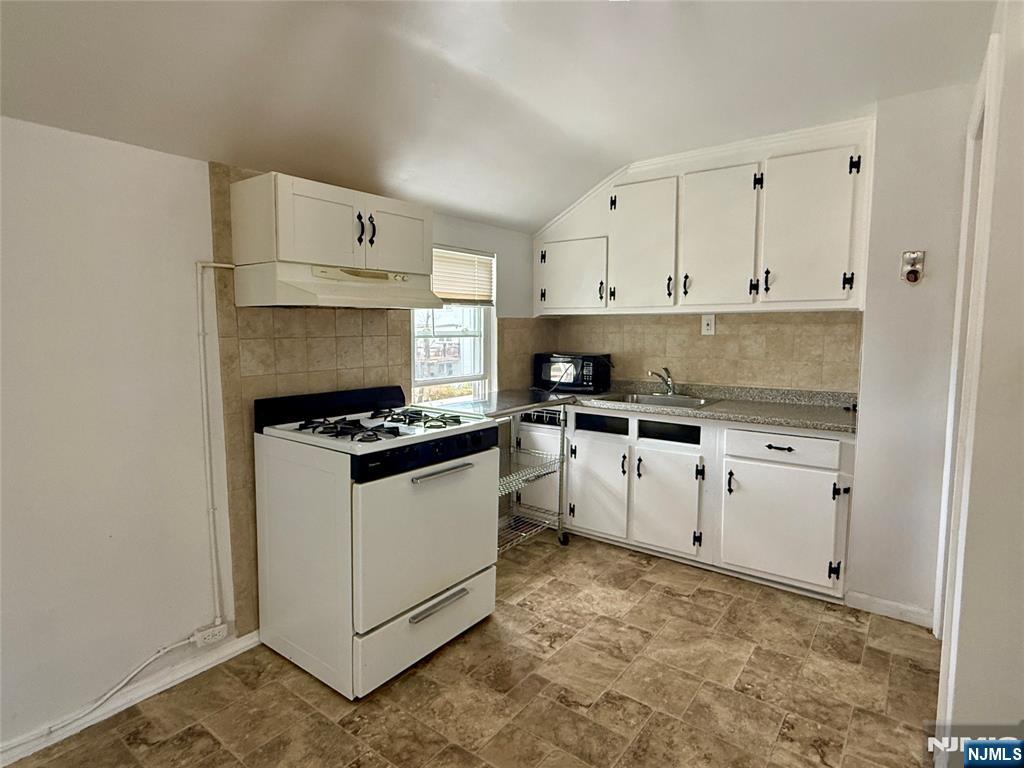 47 MacArthur Avenue, Unit 2 Lodi, NJ 07644 - Photo 5 of 6 a kitchen with granite countertop a white stove and white cabinets