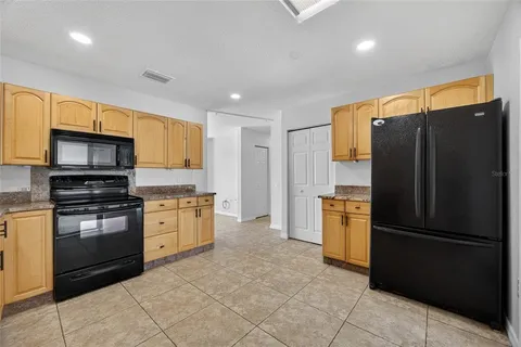 a kitchen with granite countertop a refrigerator and a stove top oven