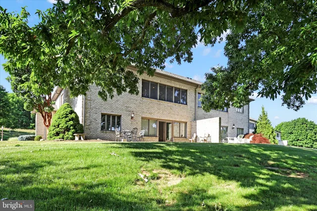 a view of house in front of a big yard with large trees