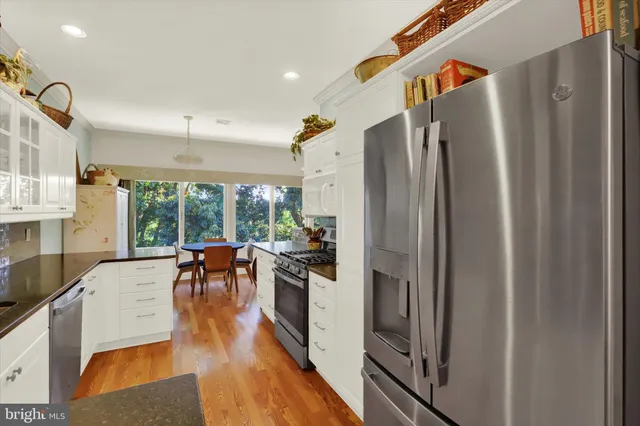 a kitchen with stainless steel appliances granite countertop a refrigerator a stove and a wooden floors