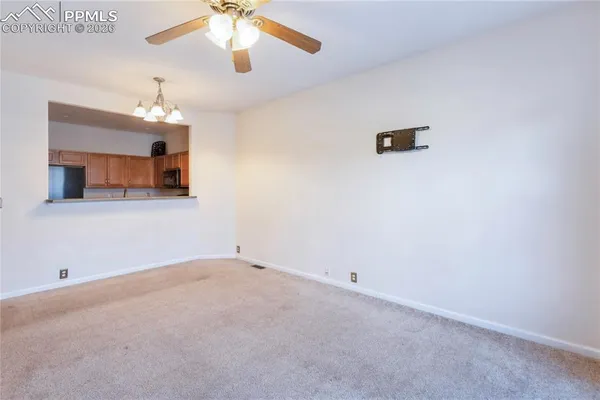 an empty room with a chandelier fan and windows