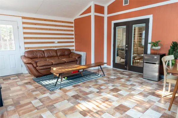 a living room with a desk a rug and a window