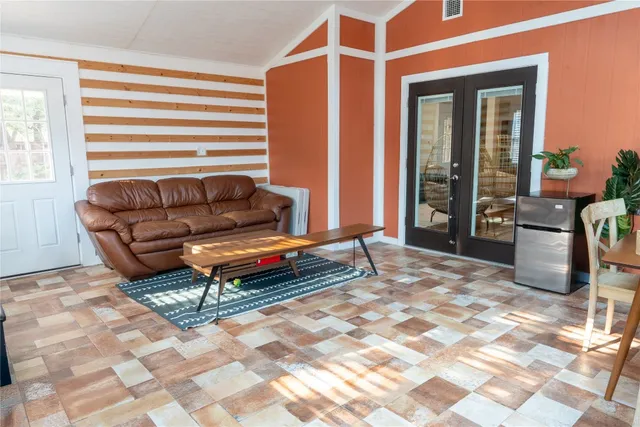 a living room with a desk a rug and a window