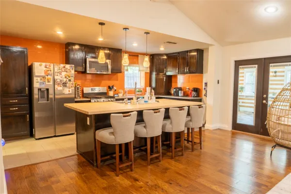 a dining hall with stainless steel appliances kitchen island granite countertop a dining table chairs and view living room