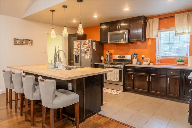 a kitchen with stainless steel appliances granite countertop a stove a sink a microwave a dining table and chairs