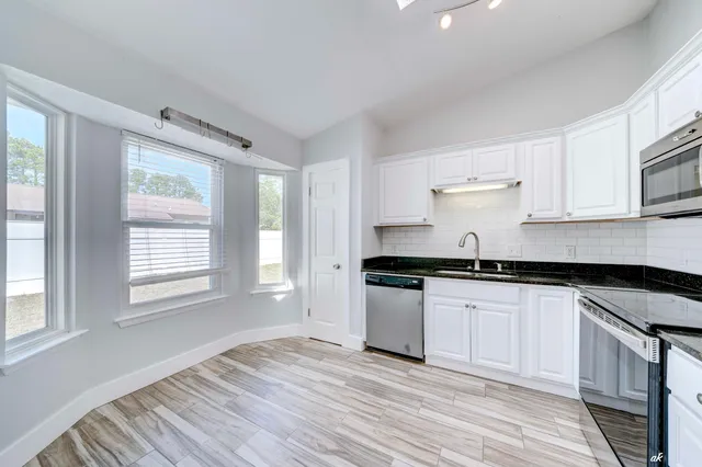 a kitchen with granite countertop a stove a sink and a refrigerator