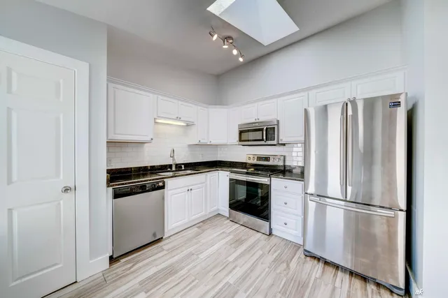 a kitchen with granite countertop a refrigerator stove and sink