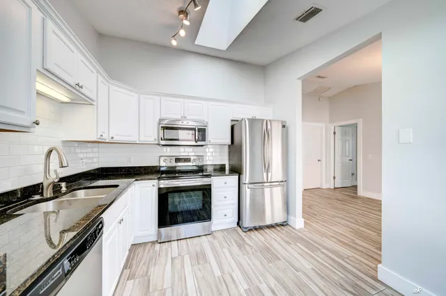 a kitchen with granite countertop a refrigerator stove and sink