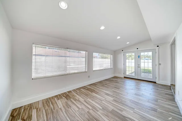a view of an empty room with wooden floor and a window