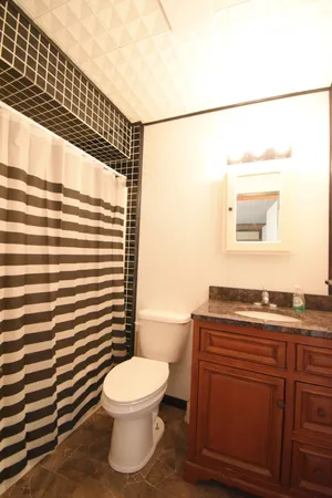 a bathroom with a granite countertop toilet a sink and a mirror