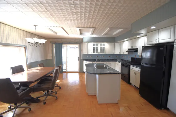 a kitchen with kitchen island a stove a refrigerator and a dining table with wooden floor