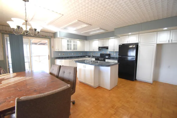 a kitchen with stainless steel appliances granite countertop a sink a stove a refrigerator a washer dryer and a dining table