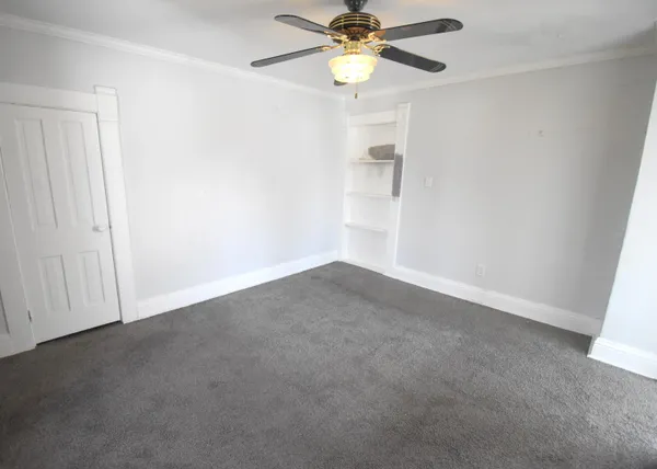 an empty room with a window and a fan