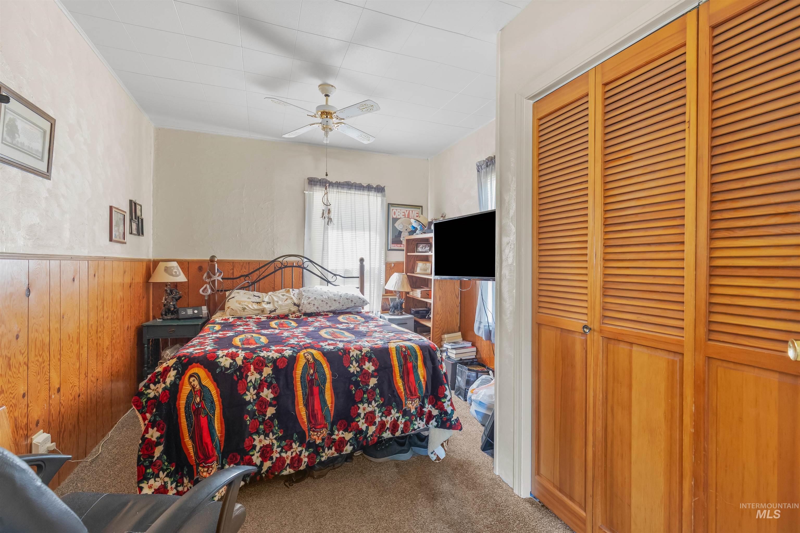 238 Hillcrest Road Lewiston, ID 83501 - Photo 27 of 27 Bedroom featuring wood-finish paneling, louvered bi-fold closet doors, a ceiling fan with integrated lighting, and neutral tone carpeting