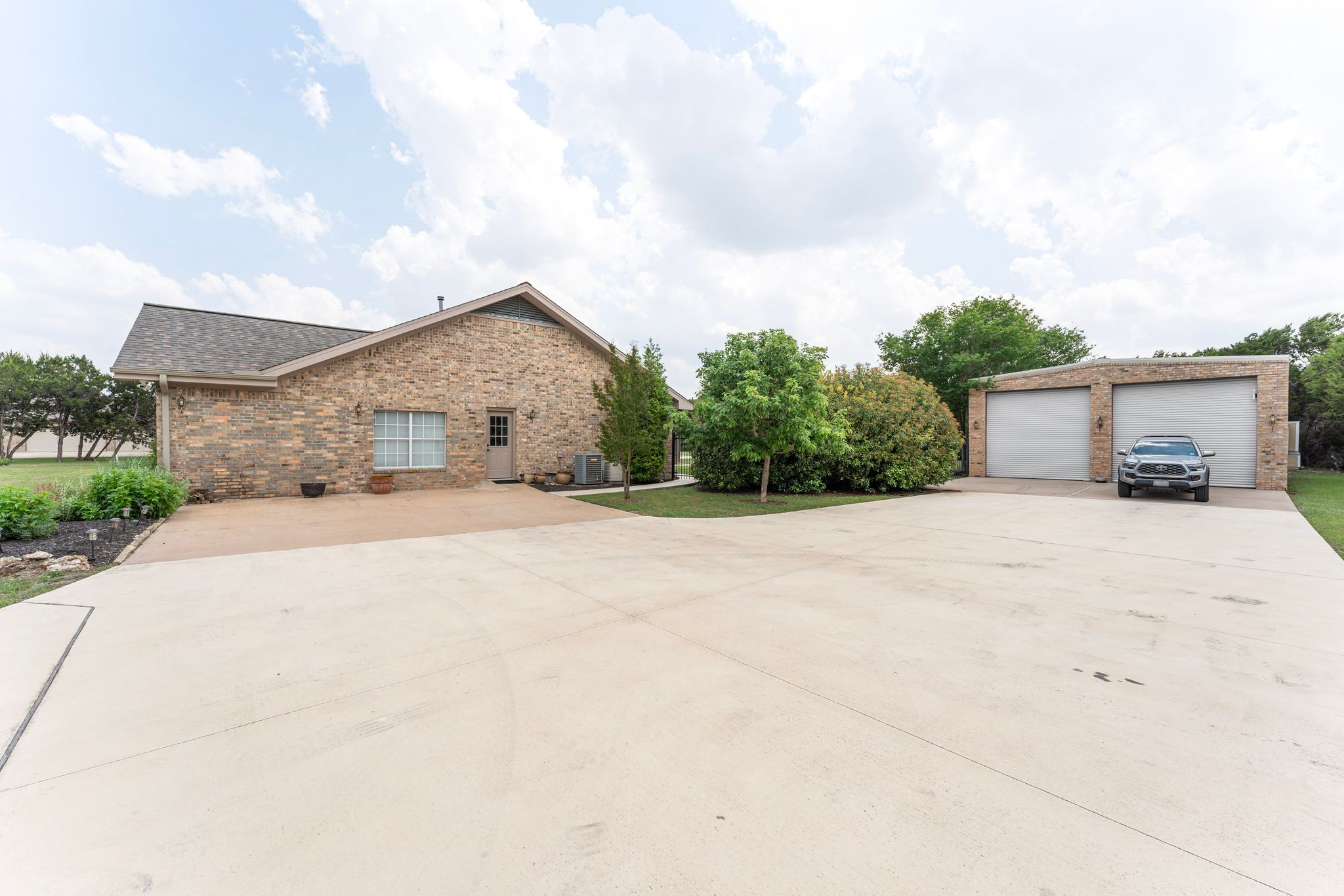 221 Breakaway Road Cedar Park, TX 78613 - Photo 18 of 39 View of home's exterior featuring brick siding, an outdoor structure, central air condition unit, and a detached garage