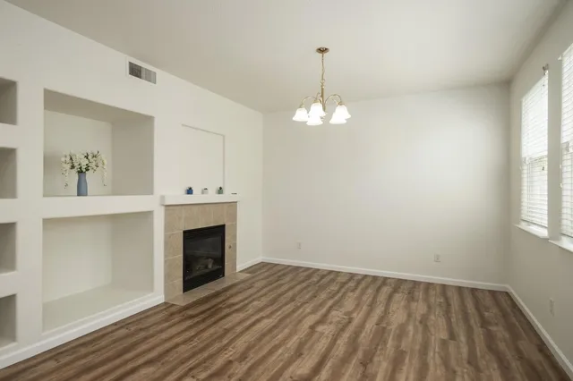 a view of an empty room with wooden floor fireplace and a window