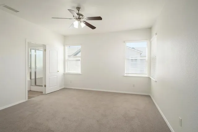 an empty room with windows and fan