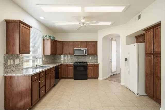 a large kitchen with stainless steel appliances granite countertop a refrigerator and a sink