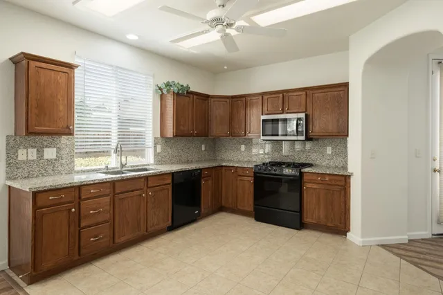 a kitchen with stainless steel appliances granite countertop a stove sink microwave and window