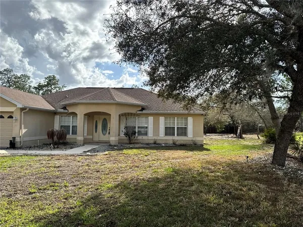 a front view of house with yard and trees around