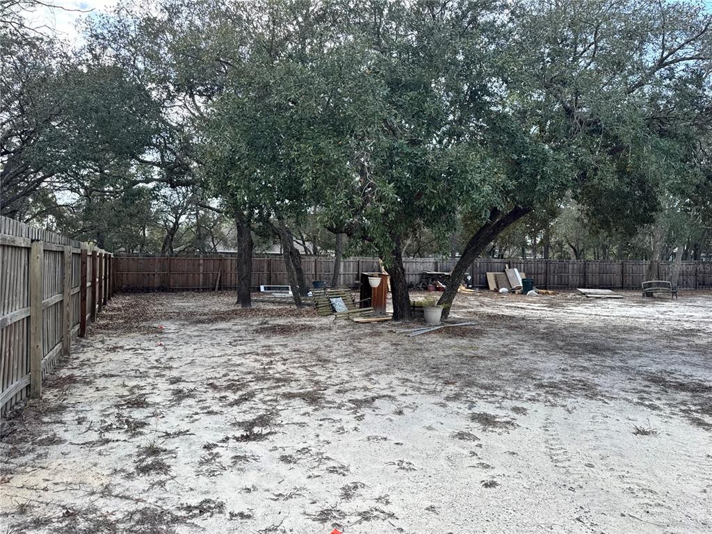 12055 Robina Road Weeki Wachee, FL 34614 - Photo 23 of 64 a view of a backyard with large trees and wooden fence