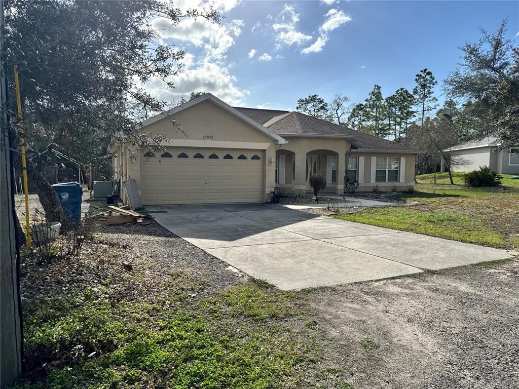 12055 Robina Road Weeki Wachee, FL 34614 - Photo 62 of 64 a front view of a house with a yard and a garage