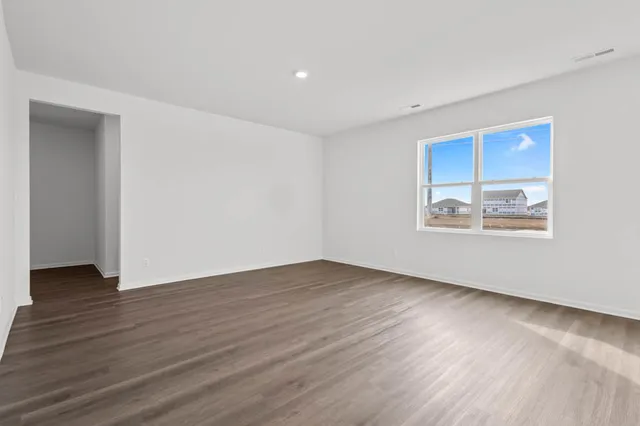 a kitchen with stainless steel appliances kitchen island granite countertop a refrigerator a stove a sink a dining table and chairs with wooden floor